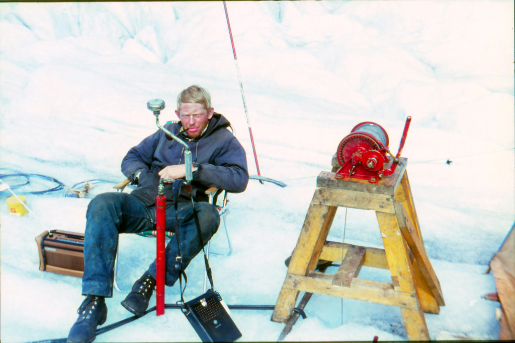 Piperøykende ung mann på isen med mye teknisk utstyr rundt seg